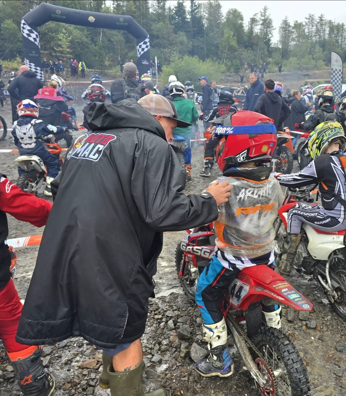 A moto parent with a young rider on the start line at a race